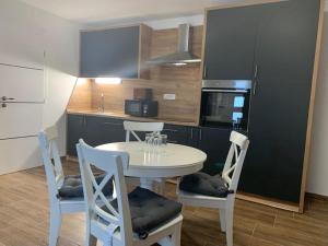 a kitchen with a white table and chairs in a kitchen at Apartmani Albatros in Perušić +17 photos