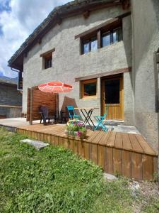 a house with a wooden deck with an umbrella and chairs at Chalet Campanule in Bonneval-sur-Arc