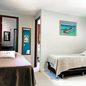 a bedroom with two beds and a painting on the wall at L&M Housing Apartamentos y casa in Búzios