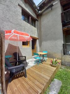 una terraza de madera con mesa y sombrilla en Chalet Campanule, en Bonneval-sur-Arc 6 fotos más
