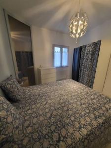 a bedroom with a bed and a chandelier at Appartement Cosy centre ville in LʼIsle-sur-la-Sorgue
