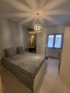 a bedroom with a bed and a chandelier at Appartement Cosy centre ville in LʼIsle-sur-la-Sorgue