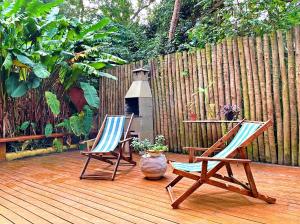 2 sillas sentadas en una terraza de madera con una valla en L&M Housing Apartamentos y casa en Búzios