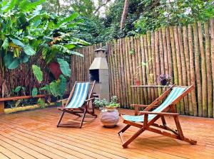 two chairs sitting on a wooden deck with a fence at L&M Housing Apartamentos y casa in Búzios