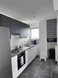 a white kitchen with a sink and a stove at Little Livia in Créteil