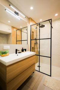La salle de bains est pourvue d'un lavabo blanc et d'une douche. dans l'établissement Glow Apartments, Apartamenty Heaven Stare Miasto, à Gdańsk