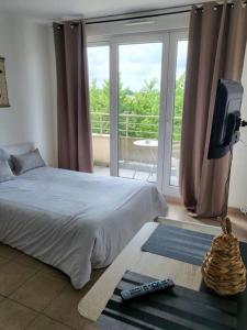 a bedroom with a bed and a television and a balcony at Disney Paris Appartement in Montévrain