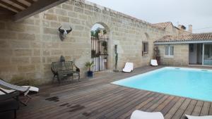 a patio with a swimming pool on a wooden deck at La Chapelle du Domaine de Choisy in Abzac