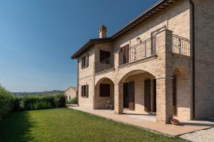 un gran edificio de ladrillo con balcón y patio en Agriturismo San Nicolino, en Offida