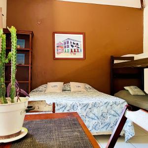 ein Schlafzimmer mit einem Bett und einer Topfpflanze in der Unterkunft L&M Housing Apartamentos y casa in Búzios