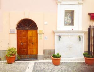 ein Gebäude mit einer Holztür und zwei Topfpflanzen in der Unterkunft B&B Piazza Fratti in Civitavecchia