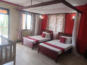 two beds in a room with red walls and windows at Lambada Holiday Resort Mombasa in Mtwapa