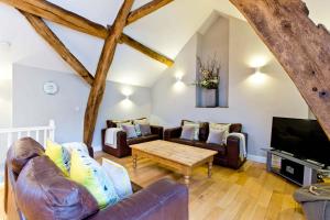 a living room with couches and a tv and a table at Cruck'd Barn in Buxton