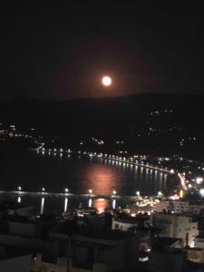 une pleine lune se levant au-dessus d'une ville la nuit dans l'établissement Terrace house, à Siteía