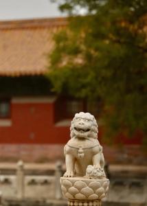 une statue de lion en pierre devant un bâtiment dans l'établissement The East Hotel-Very close to the Drum Tower,The Lama Temple,Houhai Bar Street,and the Forbidden City,There are many old Beijing hutongs around the hotel Experience the culture of old Beijing hutongs,Near Exit A of Shichahai on Metro Line 8, à Pékin