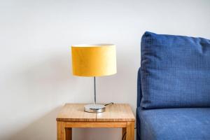 a lamp on a table next to a blue couch at GuestReady - Penthouse Flat in Trendy Peckham in London