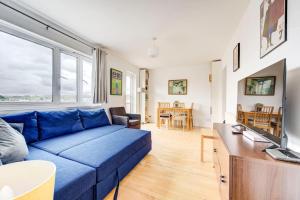 a living room with a blue couch and a tv at GuestReady - Penthouse Flat in Trendy Peckham in London