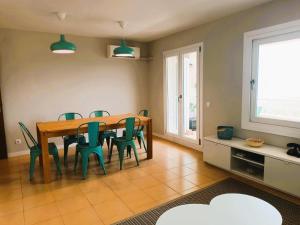 a dining room with a wooden table and green chairs at Villa Service - Coral III in El Vendrell