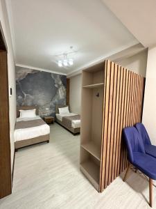 Habitación con 2 camas y una silla morada. en Lumarc Hotel en Bishkek