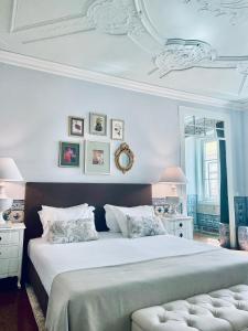 a white bedroom with a large bed and a mirror at Palacio Ramalhete in Lisbon