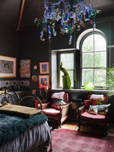 a bedroom with a bed and a chandelier and chairs at Alpine Apartments Snowdonia in Betws-y-coed