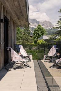 a row of lounge chairs on a balcony with mountains at GOING TRIPLE A apartments WEST in Going am Wilden Kaiser
