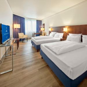 a hotel room with two beds and a flat screen tv at Best Western Hotel Trier City in Trier