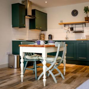 a kitchen with green cabinets and a table and chairs at Spacious 1-bed apartment with super king or twin in central Charlbury, Cotswolds in Charlbury