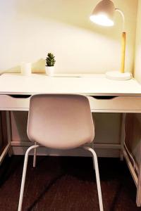 una scrivania bianca con una sedia e una pianta sopra di Appartement Terrasse 17 m² Centre historique a Lons-le-Saunier