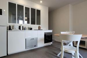 una cucina con armadi bianchi, tavolo e sedia di Appartement Terrasse 17 m² Centre historique a Lons-le-Saunier
