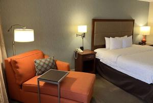 a hotel room with a bed and a chair and a phone at Wingate by Wyndham St Louis Airport in Saint Ann