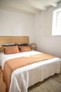 a white bedroom with a large bed with orange pillows at Vumba Agroturismo in Arganil