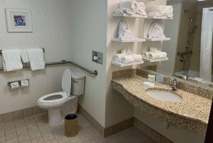 a bathroom with a toilet and a sink with towels at Wingate by Wyndham St Louis Airport in Saint Ann