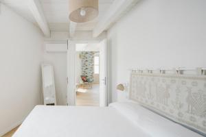 Dormitorio blanco con cama y pasillo en AltaMarea - Ampi spazi in Centro storico en Carloforte