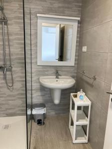 a bathroom with a sink and a mirror and a shower at Apartamentos Playa de Nemiña in Nemiña