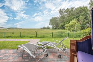 a couple of chairs sitting on a brick patio at Bungalow Neuwarft, Wohnung 2 in Dagebüll