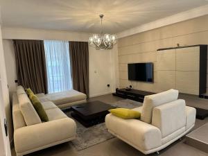 a living room with two white couches and a television at Boutique Hotel Whisky in Tirana