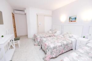 Habitación blanca con 2 camas y escritorio. en Hostal Ramos en Barcelona