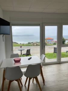 uma sala de jantar com mesa e cadeiras e vista para o oceano em Apartamentos Playa de Nemiña em Nemiña