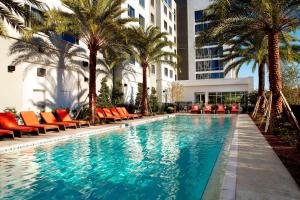 a swimming pool with orange chairs and palm trees at Courtyard by Marriott Orlando Lake Nona in Orlando