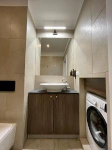a bathroom with a sink and a washing machine at Golden Queen Apartments City Center in Krakow