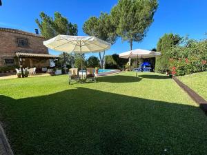 eine Liegewiese mit zwei Stühlen, einem Sonnenschirm und einem Pool in der Unterkunft Casa Rural Cupiana Piscina privada Malaga in Málaga