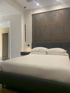 ナポリにあるNapolidayの白い大型ベッドと壁が備わるベッドルーム1室が備わります。