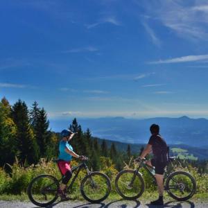 dos personas montando bicicletas en la cima de una montaña en Ruška koča en Hočko Pohorje