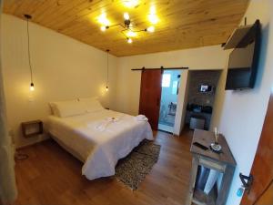 a bedroom with a white bed and a wooden ceiling at Chalé dos Pellizzari in Monte Verde