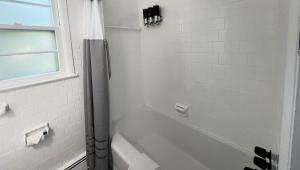 een witte badkamer met een bad en een raam bij Motel Luzerne in Lake Luzerne