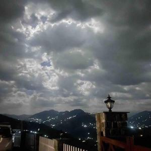 a cloudy sky with a street light on top of a building at Leeladhar TranquilIty, Luxury Stone Villa in Theog