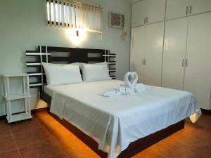 DMC2 Residence Panglao في بنغلاو: غرفة نوم بسرير ابيض مع بطانيه بيضاء