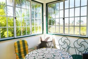Una habitación con ventanas y una mesa y sillas. en Avó das Bolachas House, en Famalicão