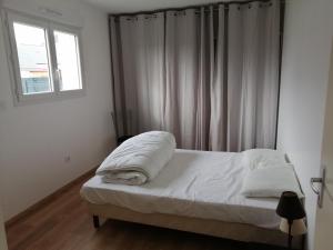 a bedroom with a bed with white sheets and a window at Maison située entre plage la mine d'or et bourg in Pénestin